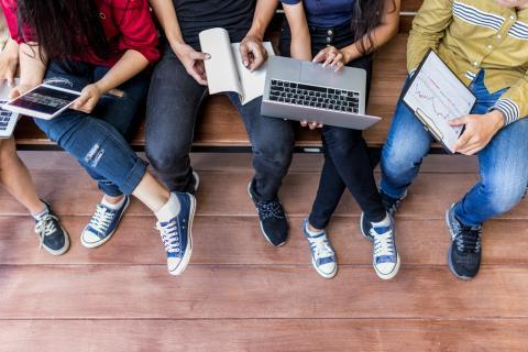 Students sit with laptops and tablets